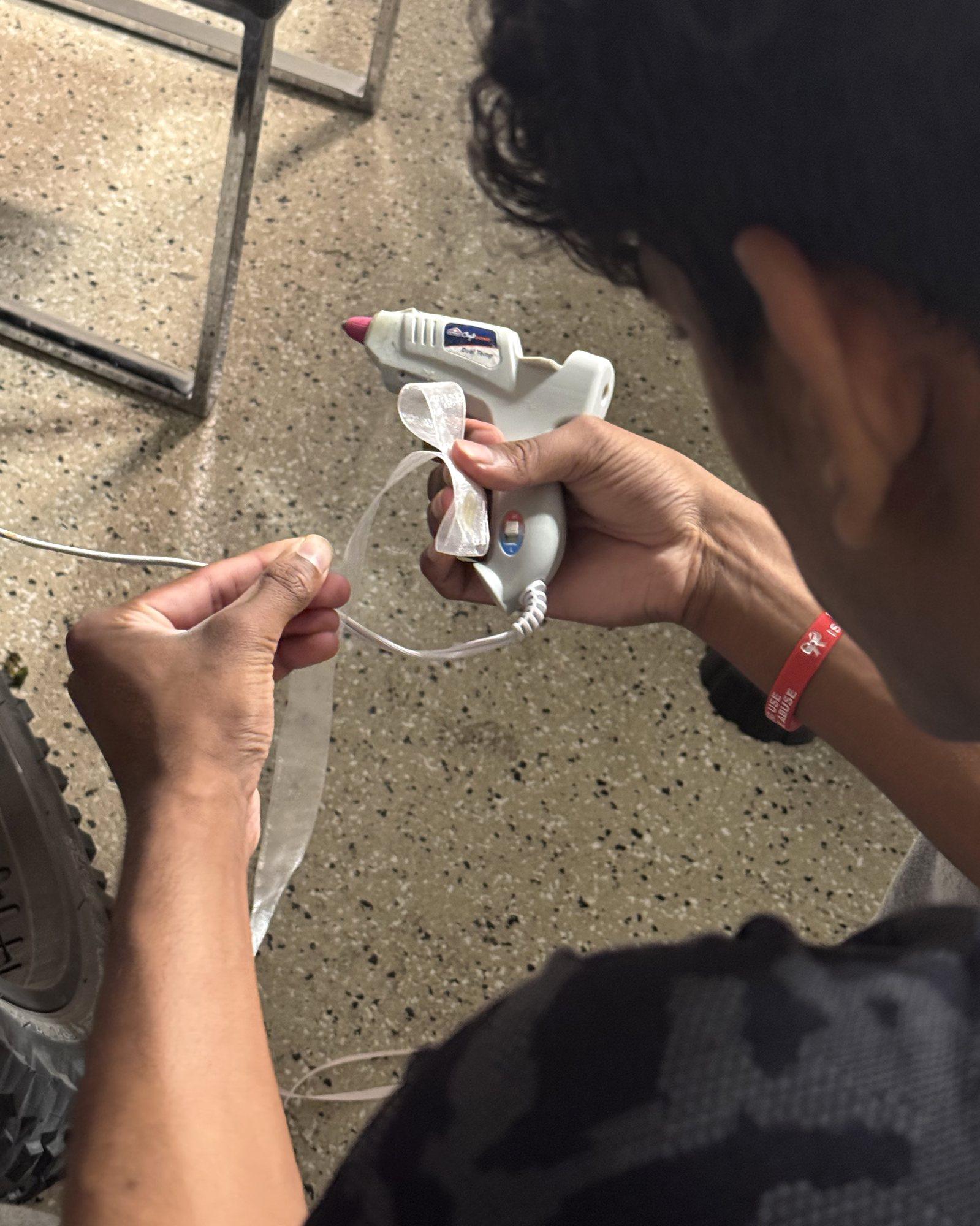 Hands gluing white ribbon in the garage workshop